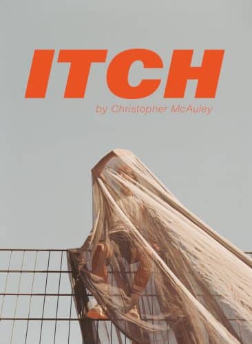 A man wearing a vest, shorts and sports shoes, balances precariously on a metal fence whilst being covered by a semi transparent mesh fabric. He is using his right arm to reach through the fabric, to try and get a better look of around him, and keep himself safe. The text - ITCH, written by Christopher McAuley - sits just above him on the fence in a bold orange colour.